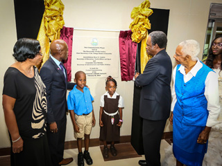 Chief Secretary Orville London unveils the plaque at the commissioning of the new Scarborough Facility on Sunday. Looking on from left are Awardee Anne Mitchell-Gift; Secretary of Education, Youth Affairs and Sport Assemblyman Huey Cadette, pupils from Scarborough RC School and Black Rock Primary School and Awardee Dr Eastlyn McKenzie.