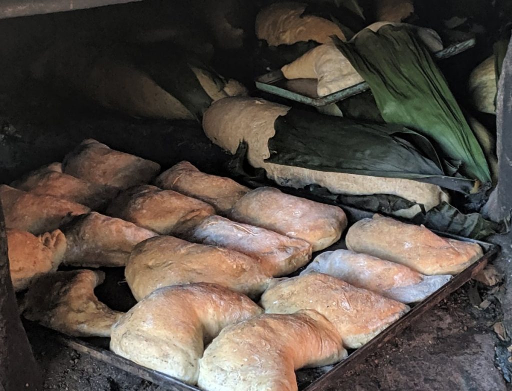 Freshly baked bread comes out of a dirt oven (2019).